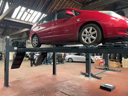 Customer car raised on a four post lift in a working garage