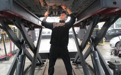 Technician working beneath a car on a scissor lift