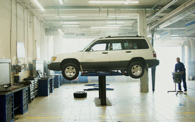 SUV raised on a single post lift in a clean service bay