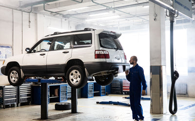 SUV raised on a two post lift in a bright service bay